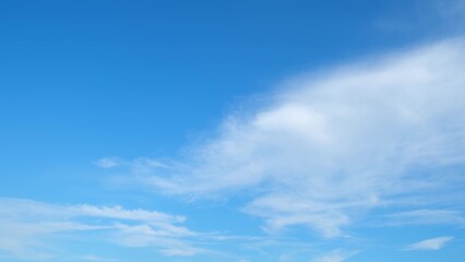 A blue sky with a few scattered, fluffy white clouds. The clouds are concentrated more on the right...