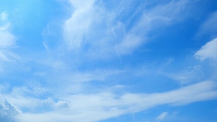 A bright blue sky with scattered white clouds, creating a serene and clear atmosphere. The clouds...