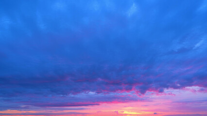 A vibrant sunrise with a sky painted in deep blues, purples, and pinks. The colors blend...