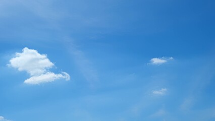 A bright blue sky with a few small, fluffy white clouds. The simplicity of the sky and the minimal...