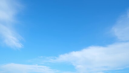 A clear blue sky with a few scattered, wispy white clouds. The sky transitions smoothly from a deeper blue at the top to a lighter blue near the horizon, creating a serene and expansive atmosphere.

