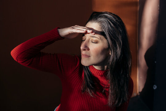 Woman shielding eyes with hand near wall