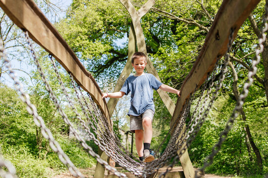 Boy walking on chain bridge at playground