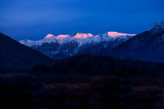 Pergine Valsugana commune with snowcapped mountains at dusk in Trento, Italy