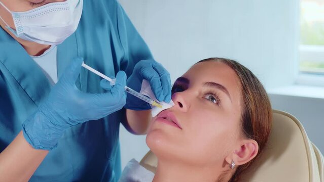 Unrecognizable circumcised cropped woman doctor performs procedure of introducing filler and correcting shape of patients lips. Close-up