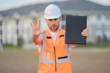 Builder with stop gesture, no hand, dangerous on building concept. Portrait of builder man. Construction worker with hardhat helmet on construction site.