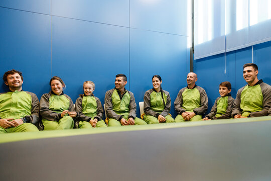 Happy participants in sportswear sitting in room of indoor skydiving center