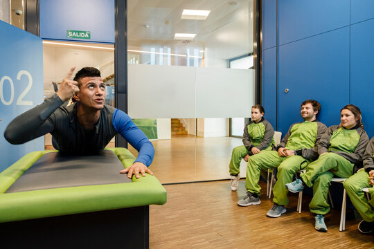 Instructor lying on table and explaining participants at indoor skydiving center