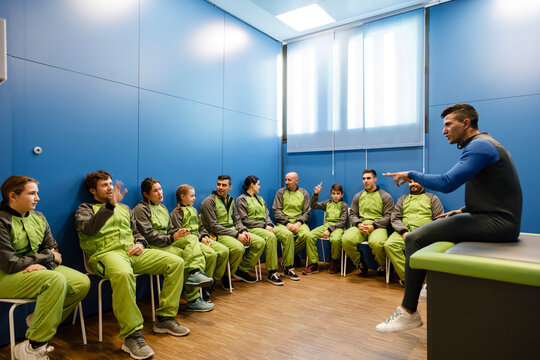 Instructor explaining people in sportswear at indoor skydiving center