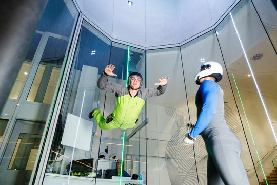 Man enjoying indoor skydiving with instructor at center