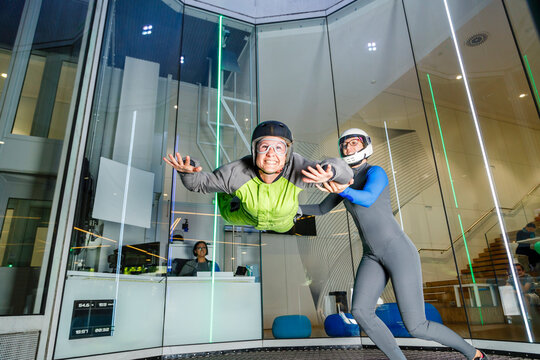Happy woman doing skydiving with assistance of instructor at skydive center