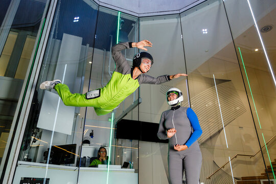 Smiling instructor with woman enjoying at indoor skydiving center