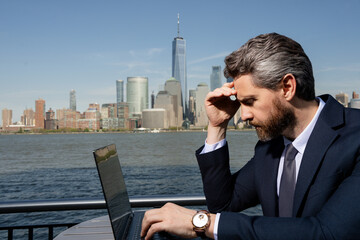 Business man using laptop outdoor in New York City. Business American success. American business dream. American businessmen in suits with laptop near Manhattan. Online business in USA.