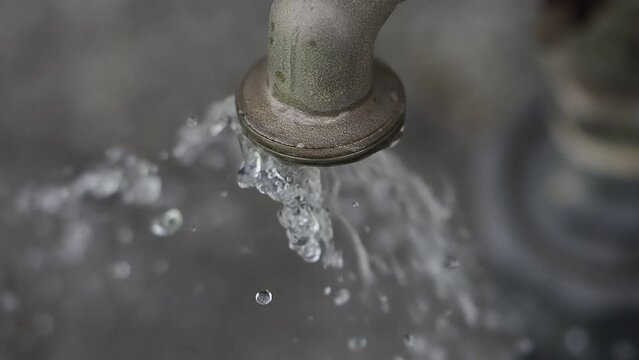 Detail of Water coming out and spraying from an old faucet slow motion