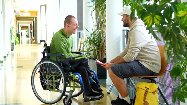 Full length video of a caucasian adult man with disability talking with a friend sitting in the university