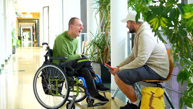 Full length video of a man with disability talking with university colleague in the corridor