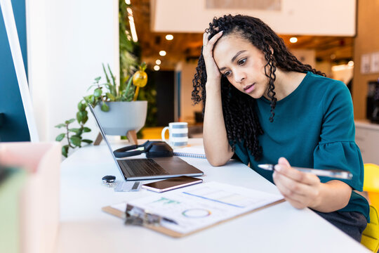Worried businesswoman with head in hand sitting at desk in office