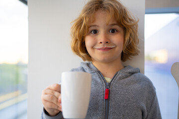 Kid holding a glass of fresh milk. Blonde caucasian Child with milk moustache drinking milk. Healthy breakfast for children. Healthy eating concept for kids. Little kid boy hold cup of milk.