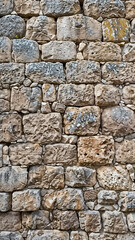 Fototapeta premium Ancient stone wall of an 18th century castle or fortress with weathered and cracked bricks in close-up view