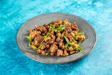 Stir Fried Green Chilli Chicken Dry served in plate isolated on blue background side view of bangladeshi food