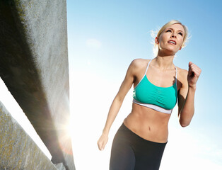 Woman, running and cardio on a road with fitness, marathon and race training outdoor. Sport, runner and urban street with athlete and exercise for health and wellness from below with city workout