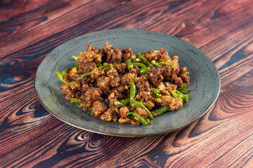 Stir Fried Green Chilli Chicken Dry served in plate isolated on wooden background closeup side view of bangladeshi food