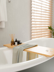 A close-up image of a luxury bathtub with bathtub tray in a contemporary, luxurious bathroom.