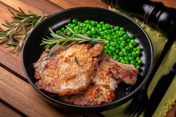 Pan fried pork chops with rosemary and  green peas.