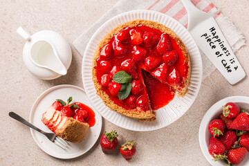 Top view of classic baked Cheesecake  with a strawberry topping sauce. Cake server where is written Happiness is the piece of cake.