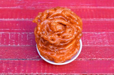 Jalebi or Jilapi in Plate Isolated on Red Wooden Background with Copy Space, Also Known as Zalabia...