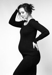 Black and white portrait of pregnant female in black dress.