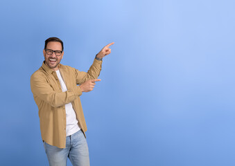 Portrait of young happy salesman aiming at copy space for marketing new product on blue background