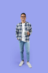 Naklejka premium Full-length Portrait of a young Asian man smiling while holding a cup standing isolated over a purple background