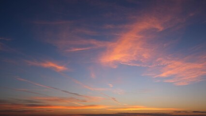 A stunning sunset with the sky painted in hues of orange and pink, fading into deeper blues. Wispy...