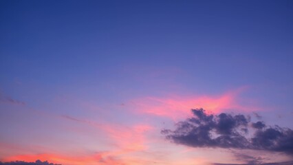 Naklejka premium A beautiful sunset with the sky bathed in vibrant shades of pink and purple. Dark clouds add contrast, enhancing the serene and tranquil ambiance of the evening sky. Sunset sky background. 
