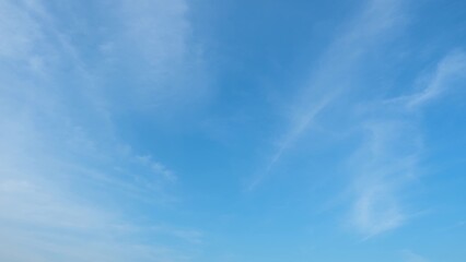 A clear blue sky with a few thin, wispy clouds stretching across it. The gradient from a light blue...