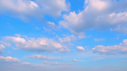 A bright blue sky scattered with fluffy white clouds. The clouds vary in size and shape, creating a picturesque and peaceful scene against the vibrant blue background. Cloud background.
