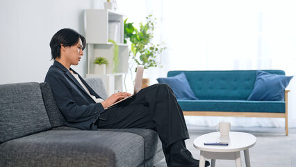 リビングでノートパソコンを使う男性