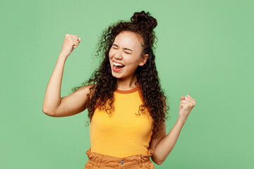 Young happy woman of African American ethnicity wear yellow tank shirt top do winner gesture...