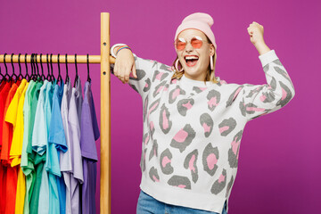 Young fun lesbian woman wear pink animal clothes show colorful t-shirts wardrobe on rack at store...