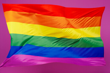 Close up photo shot of striped rainbow colorful flag isolated on pastel plain light purple violet color wall background studio. Pride day June month love LGBTQ concept. Copy space advertising mock up.