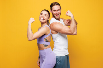 Young strong fitness trainer two man woman wearing blue clothes spend time in home gym showing...