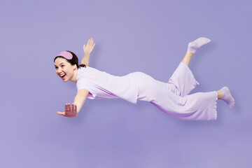 Full body side view young calm woman wear pyjamas jam sleep eye mask rest relax at home fly fall hover over air hurry up isolated on plain pastel purple background studio. Good mood night nap concept.
