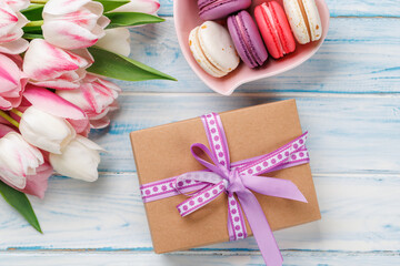 Pastel colorful tulips and vibrant macaroons fill a heart-shaped bowl