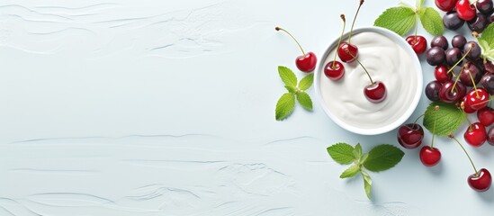 Summer dessert of yogurt topped with cherries mint and fresh berries arranged on a light concrete backdrop A selective focus is utilized for this top view copy space image