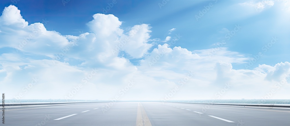 Poster blurred highway stretching into the horizon under a sky with soft blue tones and fluffy clouds suita
