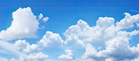 Lovely blue sky featuring fluffy white clouds against a bright and clear backdrop perfect for a copy space image
