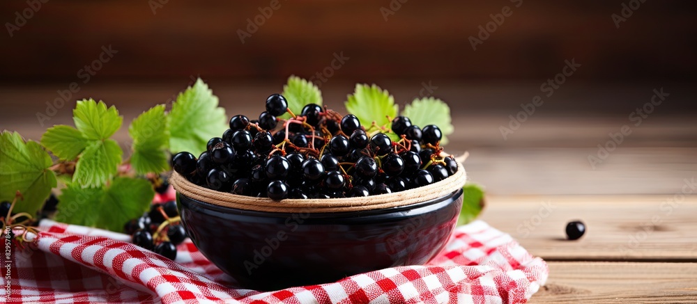 Poster close up view of ripe black currants in a bowl on a wooden table with a checkered napkin creating a 