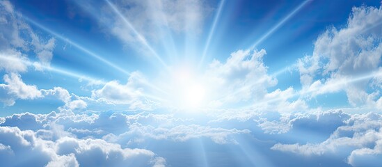Bright sun rays beaming through fluffy clouds in a clear blue sky creating a picturesque scene with copy space image