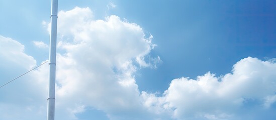 A cable stretches across poles under a lightly cloudy blue sky in a copy space image